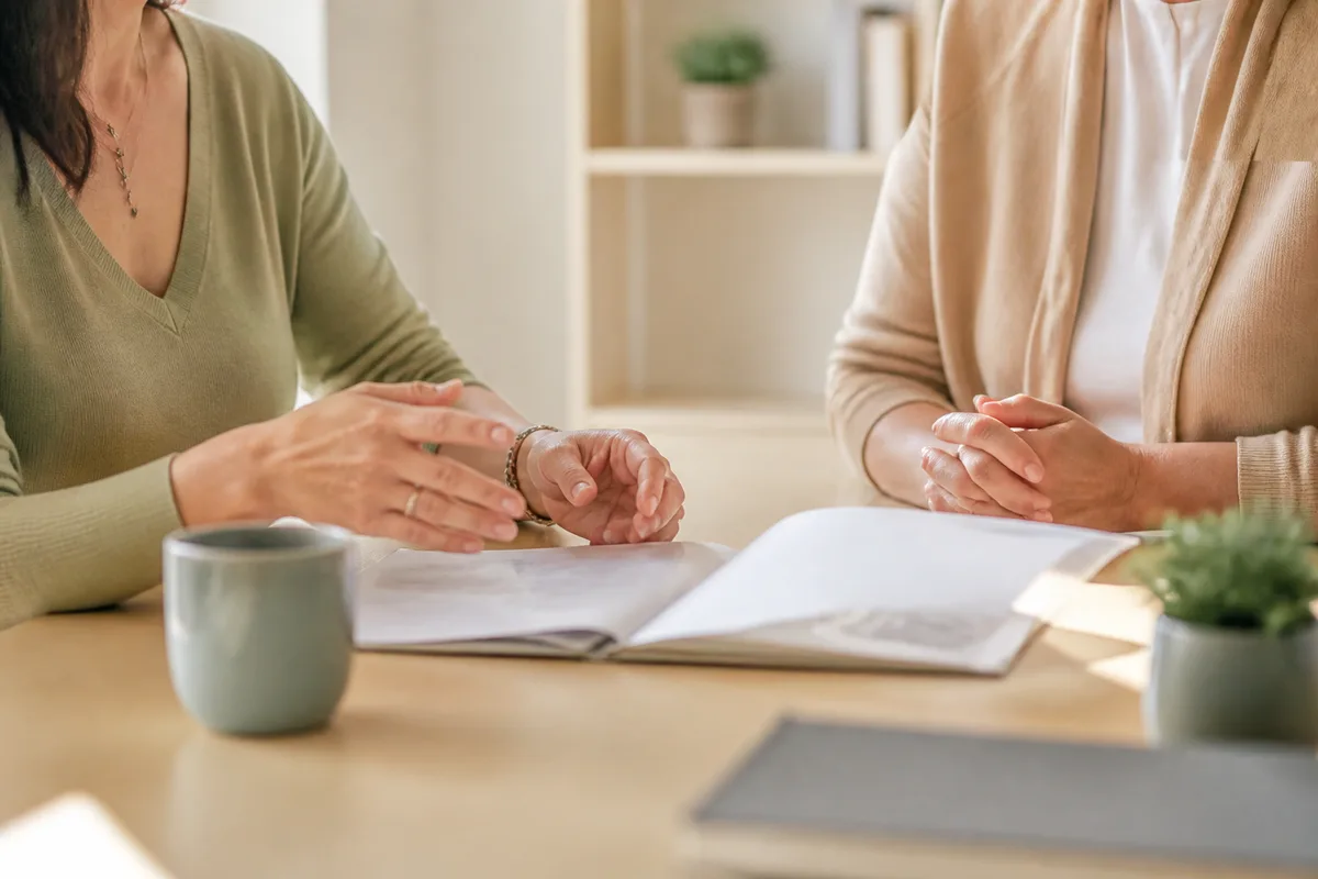 Encadrante et intervenante à domicile assises face à face dans un bureau clair, dossier ouvert sur la table